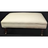 A cream upholstered ottoman, raised on turned wooden legs and brass casters, H.35cm L.95cm D.63cm