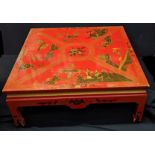 A large Chinese red lacquered coffee table, depicting landscape scenes with figures, H.43cm W.