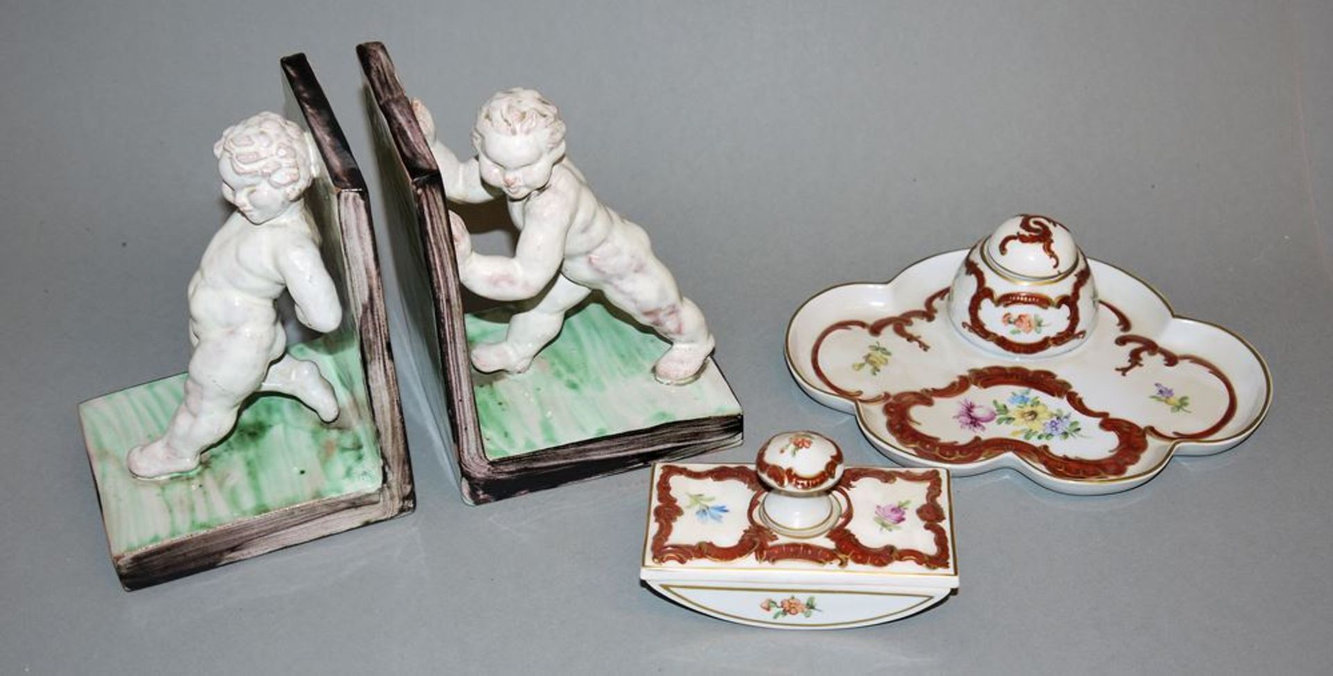 Porcelain writing set, Potschappel, Dresden, a pair of majolica bookcases with putti, probably Vien