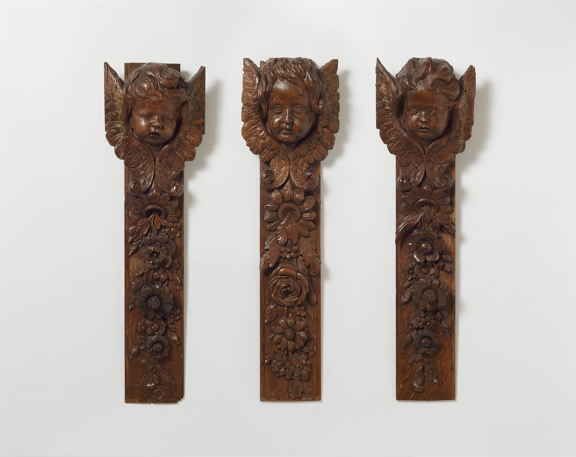 Three decorative oak panels with angels' heads