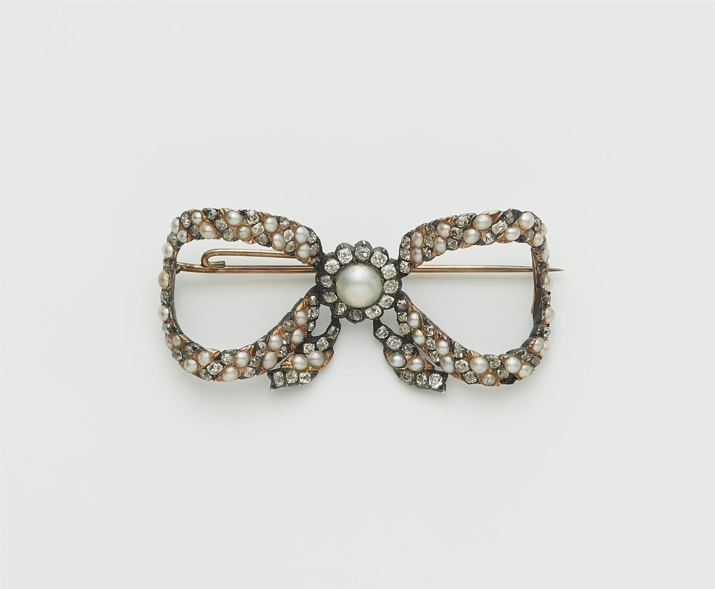 An early 19th century silver gilt pearl and cushion-cut diamond bow brooch with 14k gold mount.