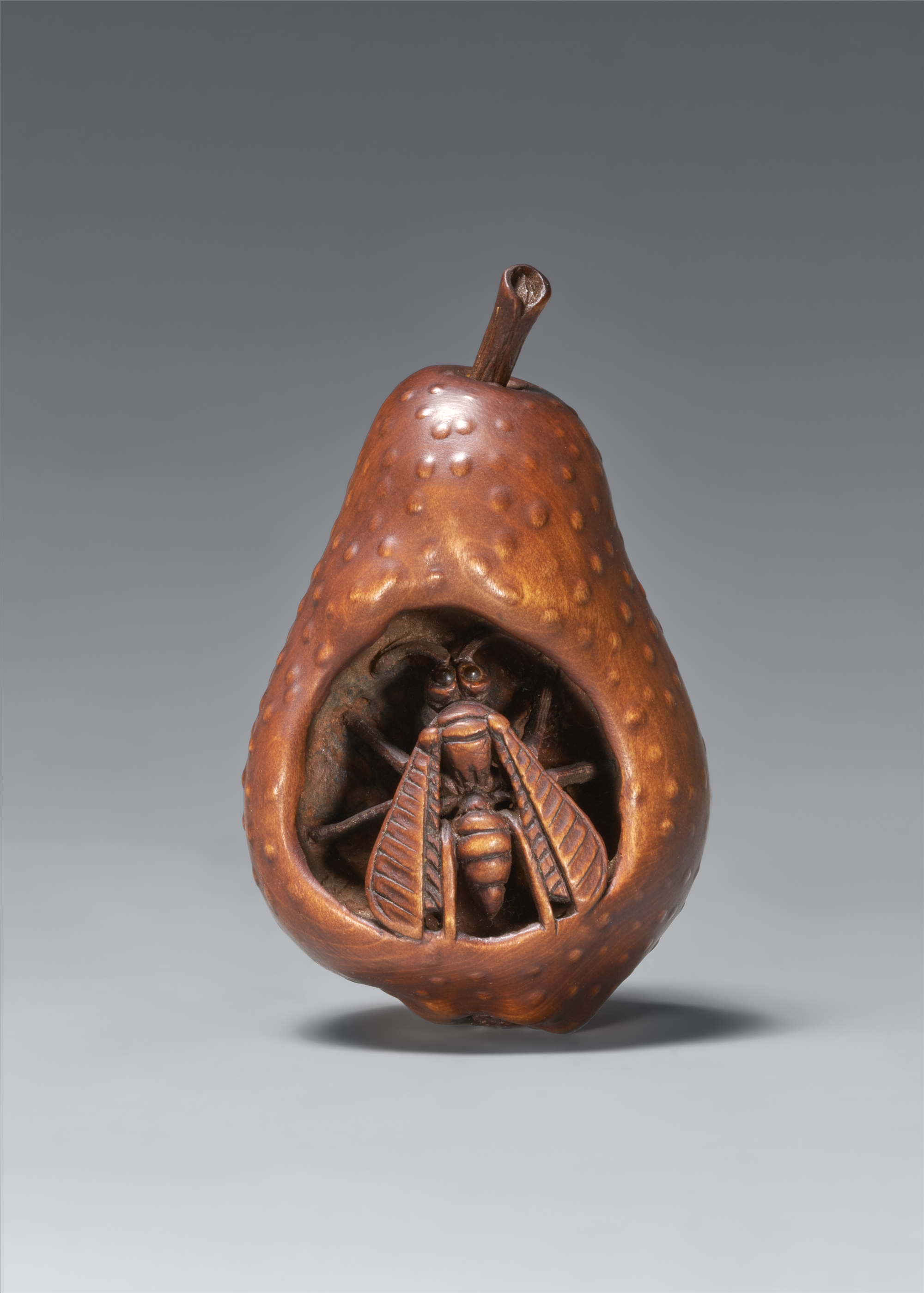 A wood netsuke of a wasp in rotting pear. In the style of Sangetsu. Nagoya. Second half 19th century