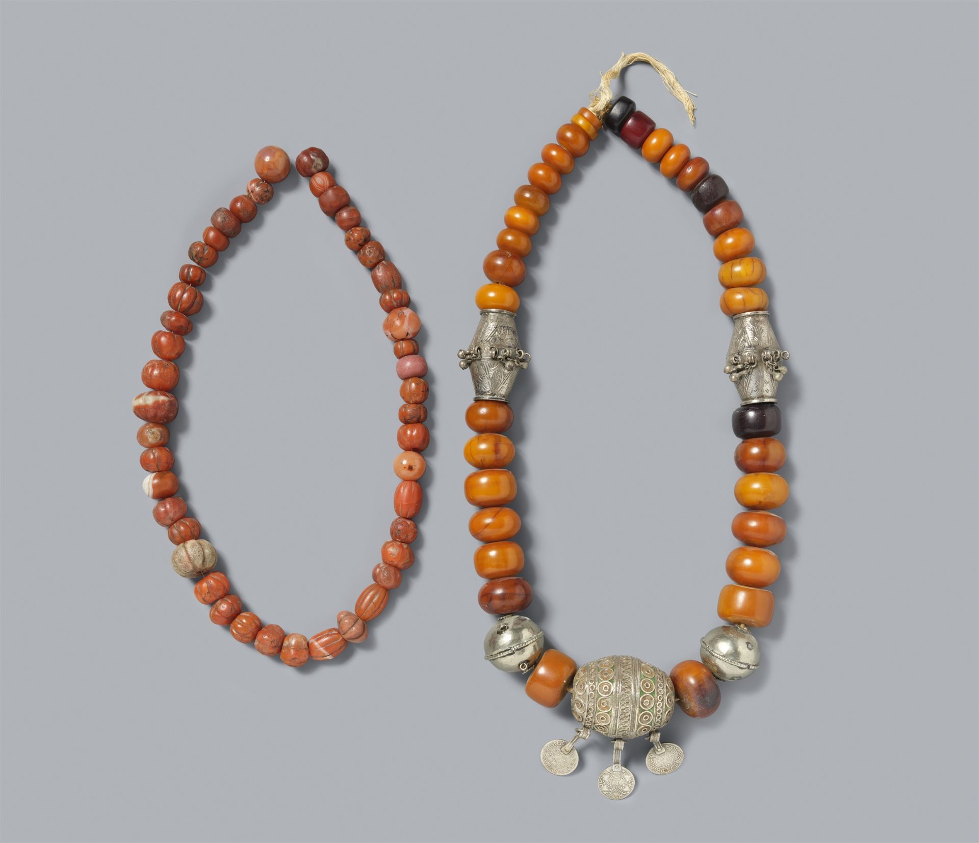 Zwei Halsketten. Bernstein und andere Harze, Silber, Koralle. Tibet
