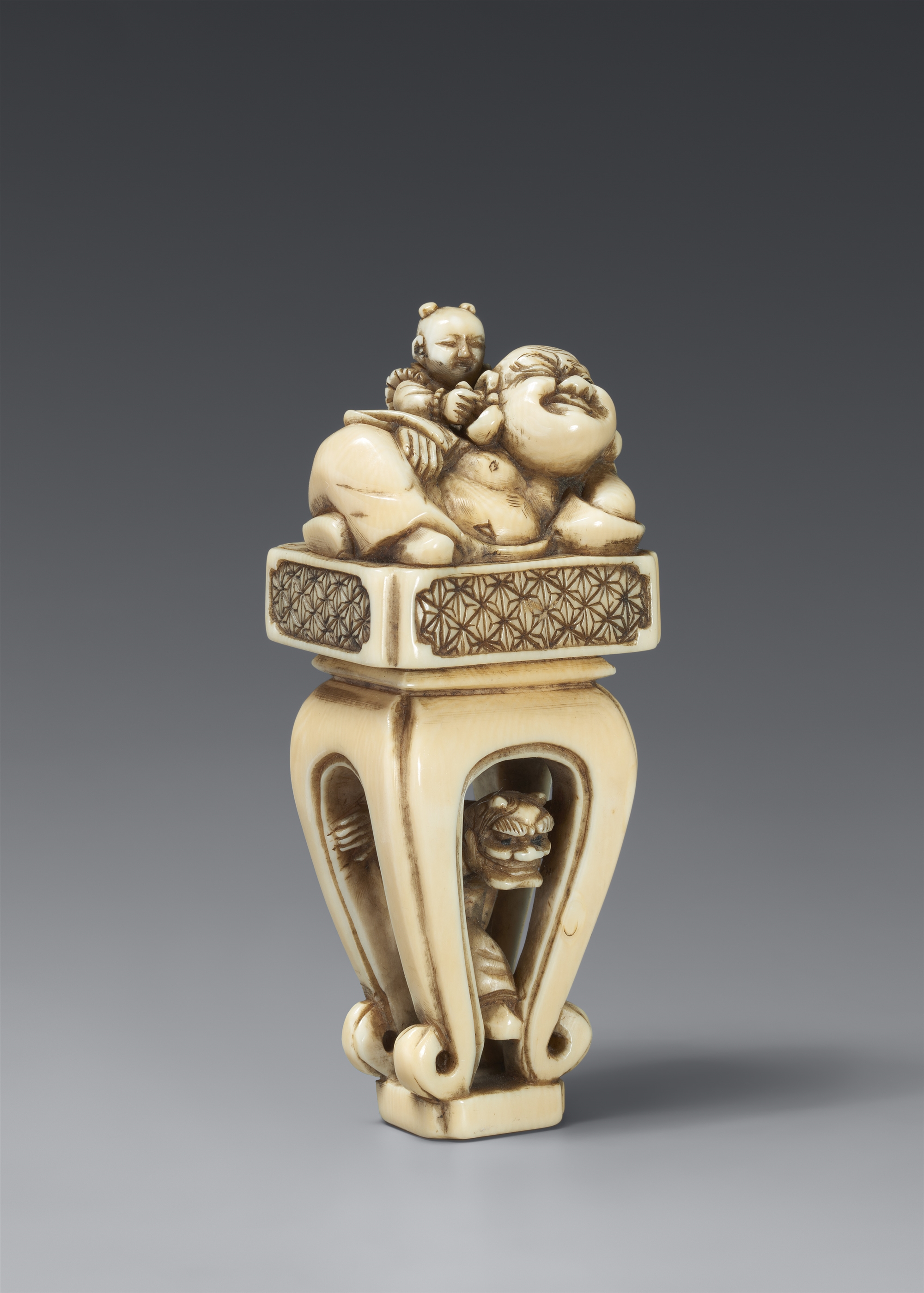 An ivory netsuke of Hotei on a high Chinese-style table. 19th century