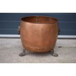 A large early 20th century copper and brass cauldron / log basket with lion's head handles and