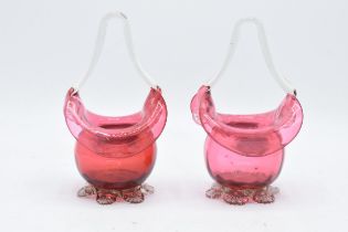 A pair of cranberry glass baskets with handle. Pontil marks to bases. 16m tall. In good condition.
