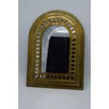 A 20th century arched brass mirror with embossed decoration. 37 x 27cm.