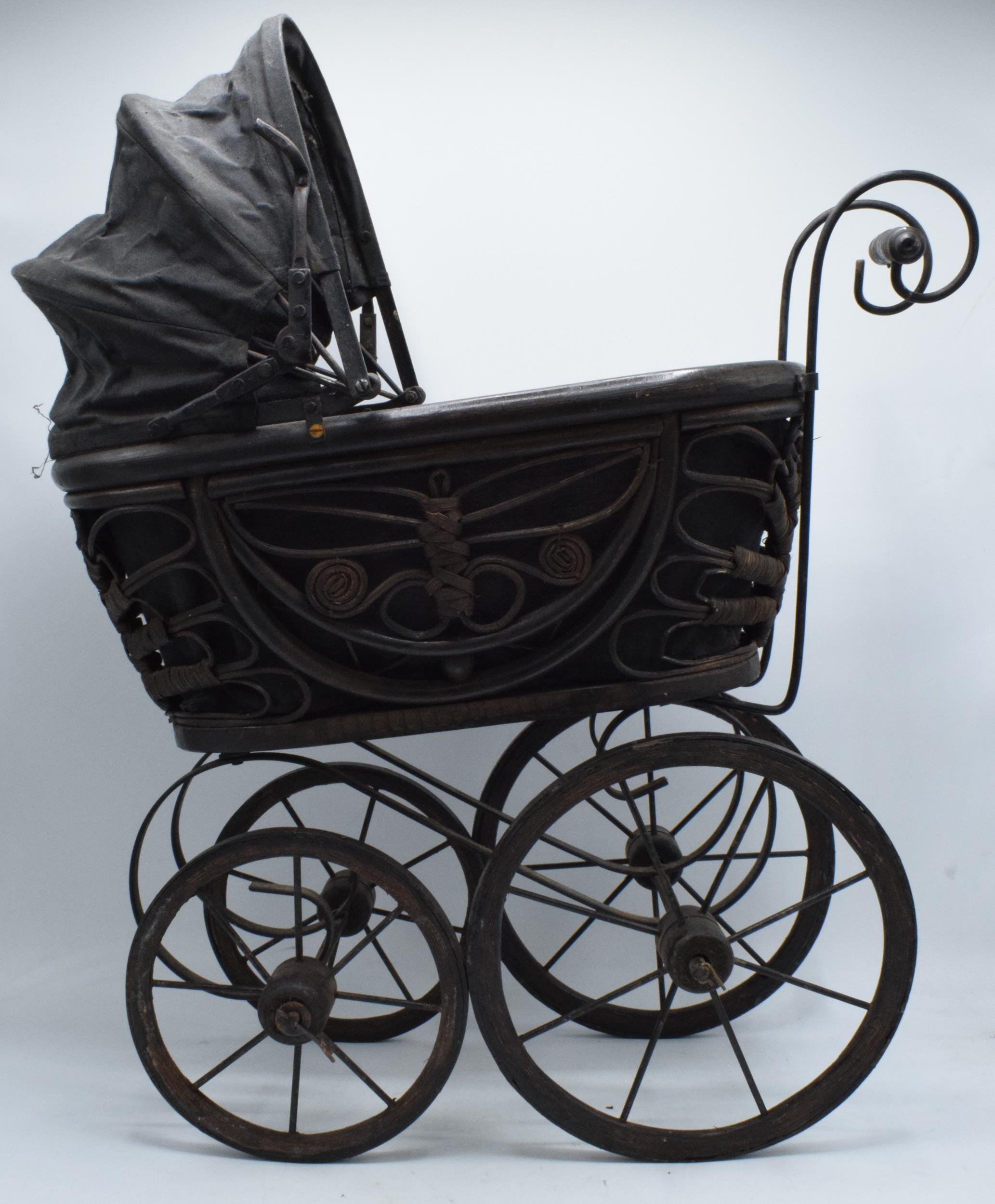 Am early to mid 20th century ornate dolls pram on wooden and metal wheels. 58cm tall.