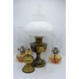 A collection of vintage oil lamps to include brass examples with associated shades and chimneys (4).