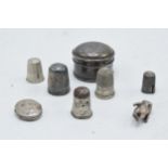 A collection of silver items to include a round pillbox, a locket, a silver thimble and other