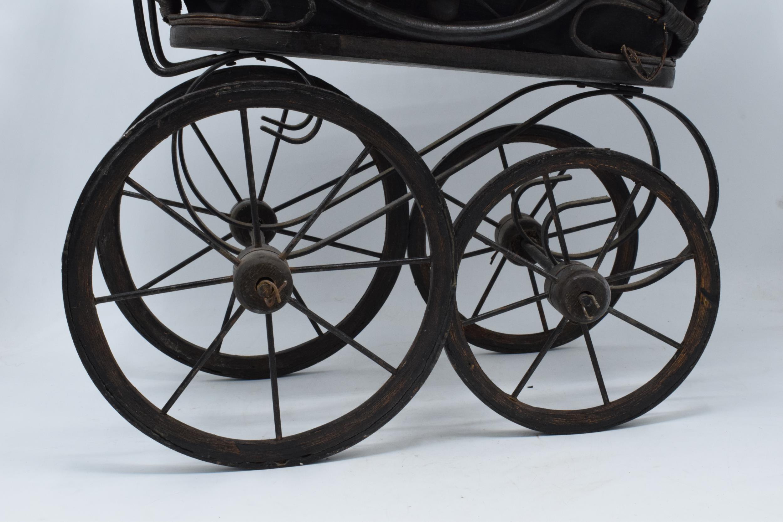 Am early to mid 20th century ornate dolls pram on wooden and metal wheels. 58cm tall. - Image 3 of 8