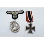 A collection of German Militaria to include a WW2 iron cross and ribbon, a reproduction Nazi cap