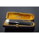 A cased cigarette holder with a silver collar. 6.5cm long.