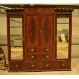 A large early 20th century inlaid mahogany triple wardrobe with central cupboards over two drawers