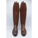 A pair of brown leather riding boots with wooden lasts marked 'Tristram Calcutta'. 57cm tall.