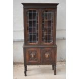 A late 19th / early 20th century wooden bookcase with carved decoration and glazed doors. 76 x 31