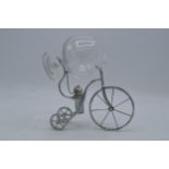 A novelty silver plated brandy warmer in the form of a tricycle / penny farthing style with a glass.
