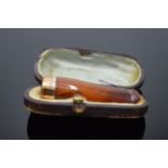 A cased amber cheroot holder with 9ct gold collar.