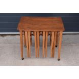 A mid century style nest of four teak tables comprising a small rectangular table on casters with