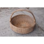 A large vintage wicker basket with curved handle. 73cm diameter.