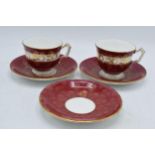 A pair of Aynsley cups and saucers together with a spare cup decorated in a majestic red and gold