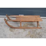 A vintage wooden and metal child's sledge in a Scandinavian style, 96cm long.