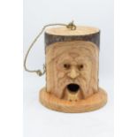 A carved and hollowed log 'Green Man' birdhouse. 23cm tall.