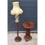 A quarter-veneered pedestal table together with a glass and brass lamp sitting on turned wooden