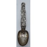 A sterling silver ornate spoon with Native American Indian face to the spoon with traditional scenes
