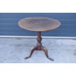 A 19th century oak tilt-top tripod table with circular top on a turned column. 70cm tall, 75cm wide.