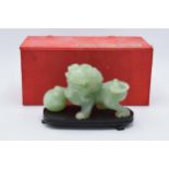 A boxed Chinese Jade (or similar) carved figure of a Dog of Fo on wooden plinth. 13cm long. In