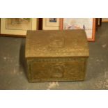 A brass chest with repousse decoration and wooden linings with lion's head handles. 40cm wide.