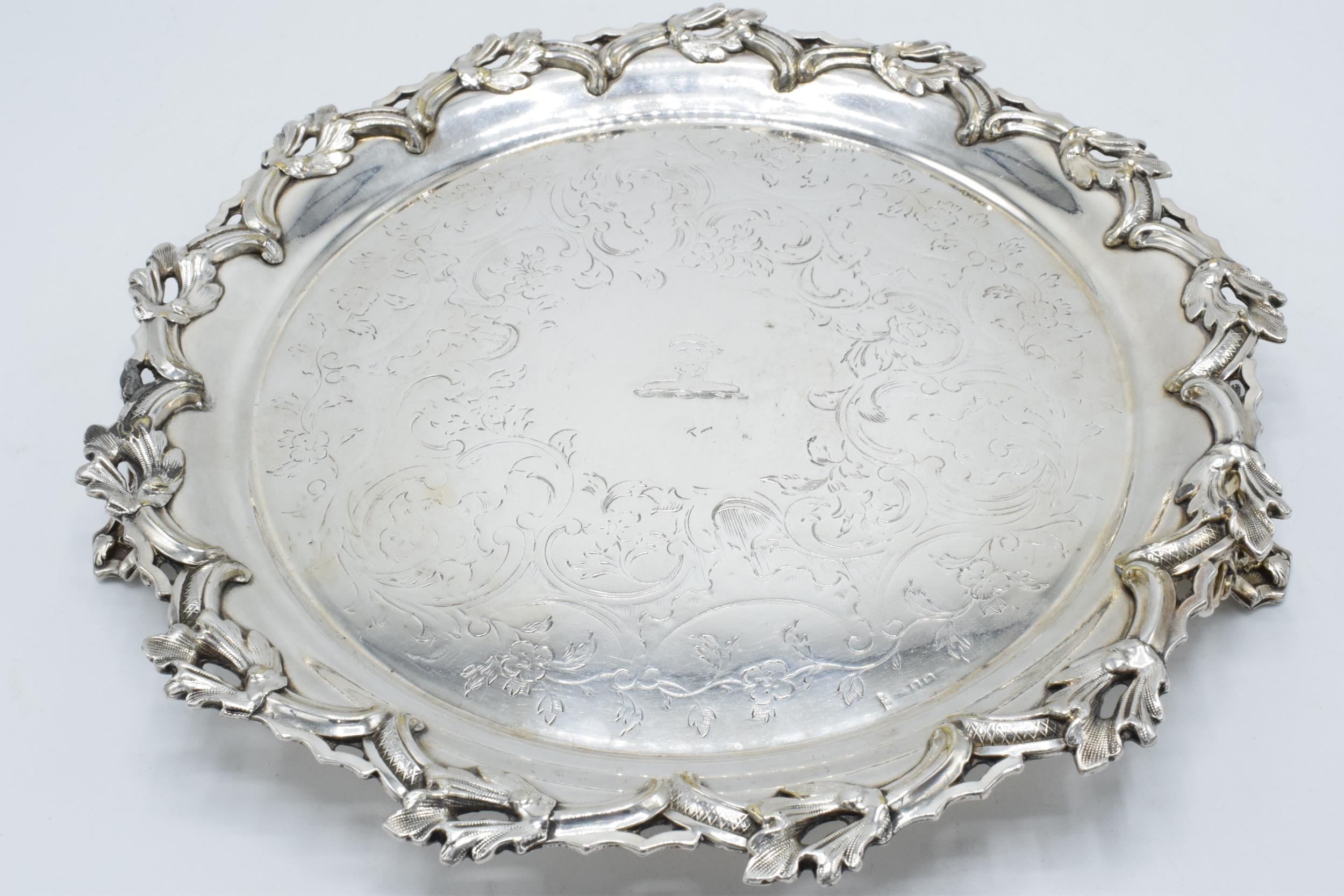 A large silver plated salver raised on three ornate feet with unusual decoration. 26cm wide.