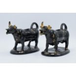 A pair of earthenware 20th century Staffordshire-style cow creamers in Jackfield manner (2) (horns