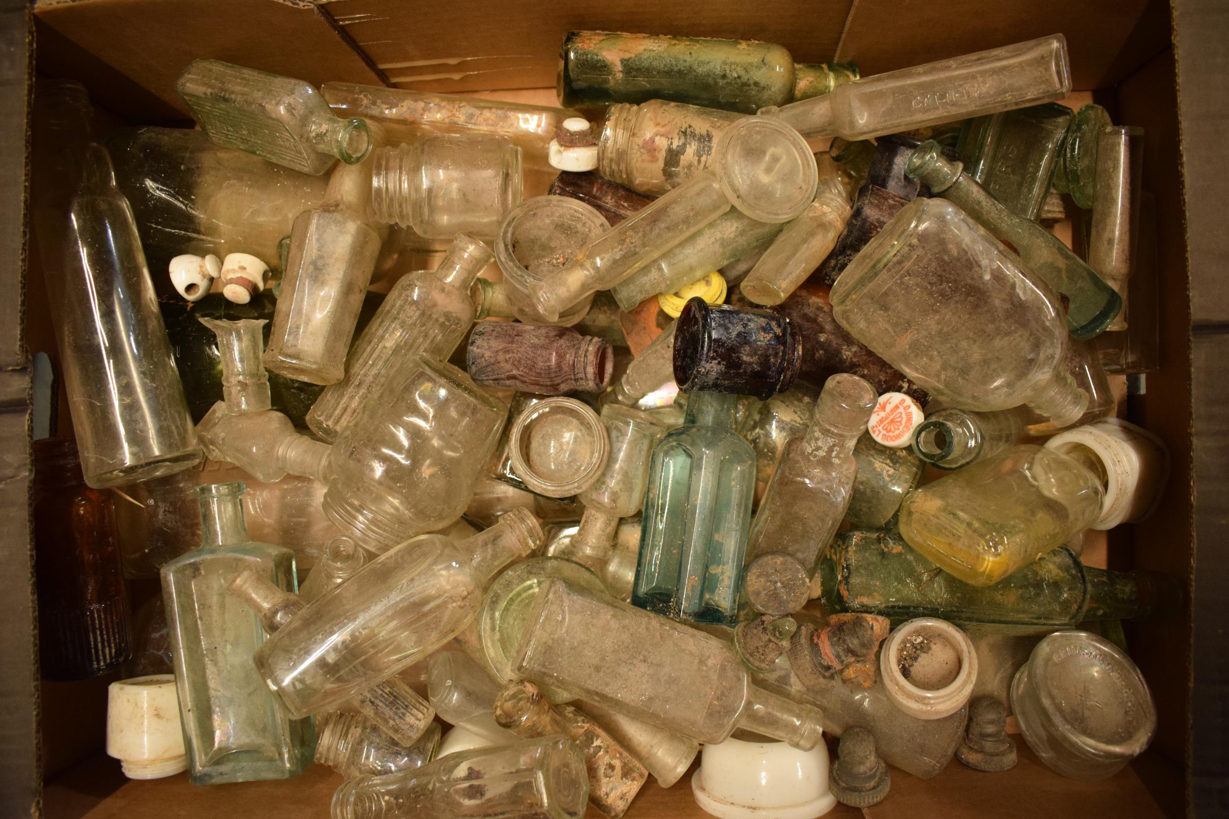 A large collection of glass bottles of varying forms and colours with some having advertising