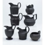 A collection of mainly 19th century black basalt cream jugs to include named examples such as
