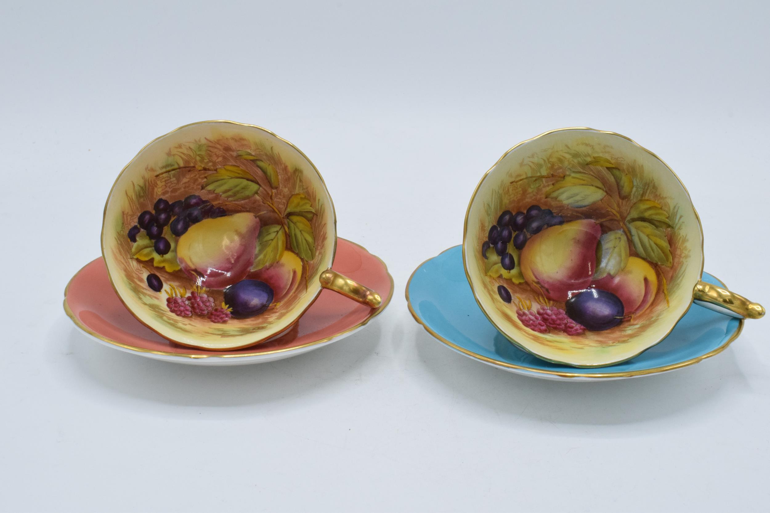 A pair of Aynsley Orchard Gold cups and saucers with coloured backgrounds, both signed D. Jones (4).