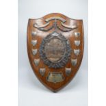 A wooden presentation shield with hallmarked silver name shields and a silver plate central relief