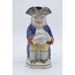 An early 19th century Staffordshire Toby jug of a man in a tricorn hat holding a jug with floral