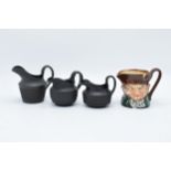 A trio of 19th century black basalt cream jugs with engineered decoration to include one of tapering