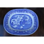 A large 19th century blue and white meat platter with transfer decoration of idealised landscape