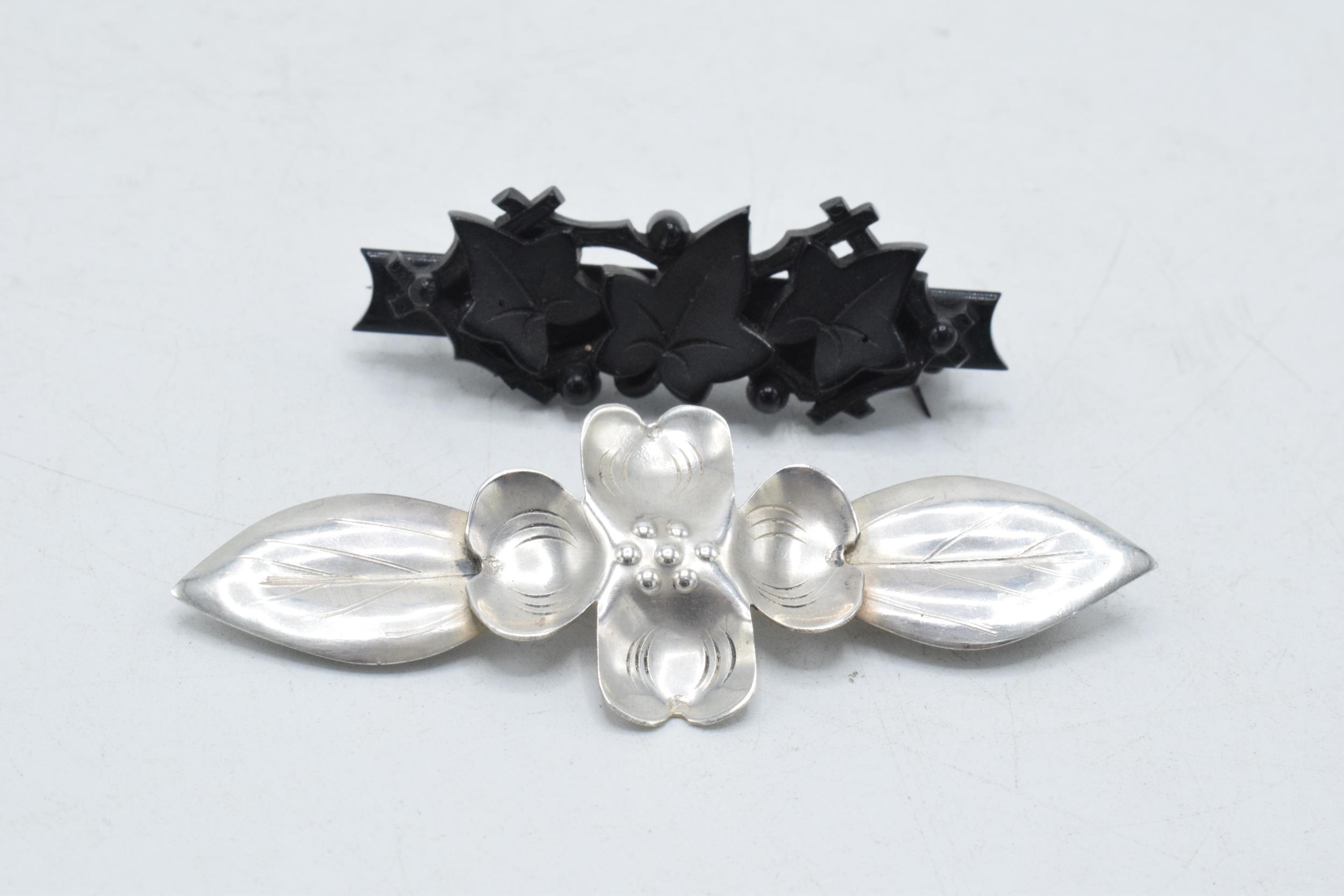 A pair of vintage brooches to include white metal stylised floral brooch and a vulcanite ivy - Image 2 of 3