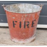 Vintage metal riveted fire bucket with swing-over handle painted red with 'FIRE' in black, 31cm tall