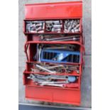 A vintage red metal folding toolbox with contents to include sockets, spanners, wrenches, impact