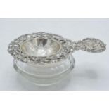 Antique hallmarked silver tea strainer and silver topped collecting glass.