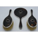 Three-piece silver and tortoiseshell dressing table set to include a hand mirror and 2 brushes,