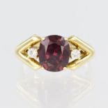 Yellow metal ring set with a central oval rubelite measuring approx. 10mm x 8mm with a single cz