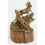 Bronze statuette of two rams standing on a rock face. Mounted on a wooden log