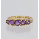 9ct yellow gold graduated five stone ring set with round purple stones (some chipped) in claw