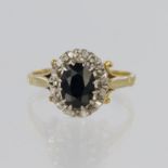 18ct yellow gold cluster ring set with a central oval sapphire measuring approx. 7mm x 5mm, with